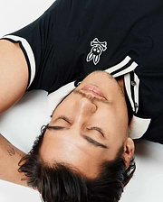Black Mens Ridley Pique Polo, classic fit, pique texture, with white ribbed collar, two-button placket, and cuffs, featuring an embroidered white Psycho Bunny skull logo on the left chest. (2)
