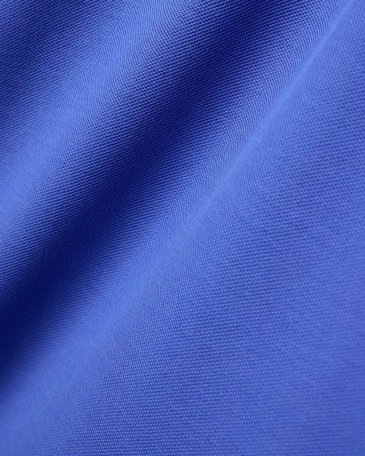 Close-up of the Mens Brad Pique Polo, featuring its vibrant royal blue color and classic textured pique knit fabric with soft, flowing folds.