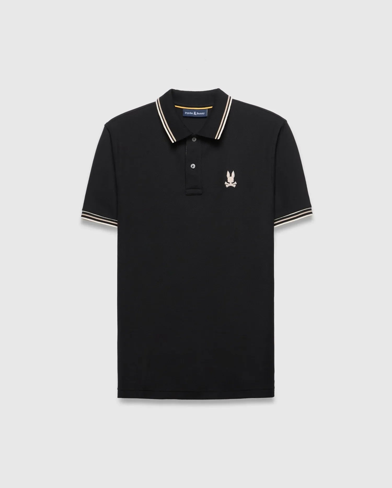 Mens Brad Pique Polo, black classic fit with white and gold striped collar and cuffs, featuring a small embroidered light pink/cream Psycho Bunny skull logo on the left chest. (5)