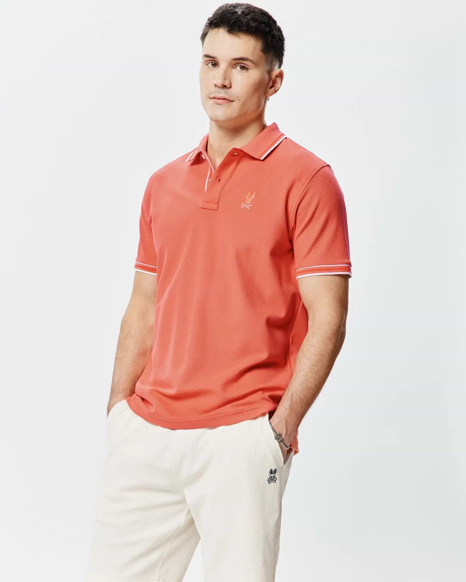 Mens Brad Pique Polo in coral, featuring a classic fit, pique knit fabric, white tipping on the collar and sleeve cuffs, and a small embroidered Psycho Bunny skull logo on the left chest. (1)