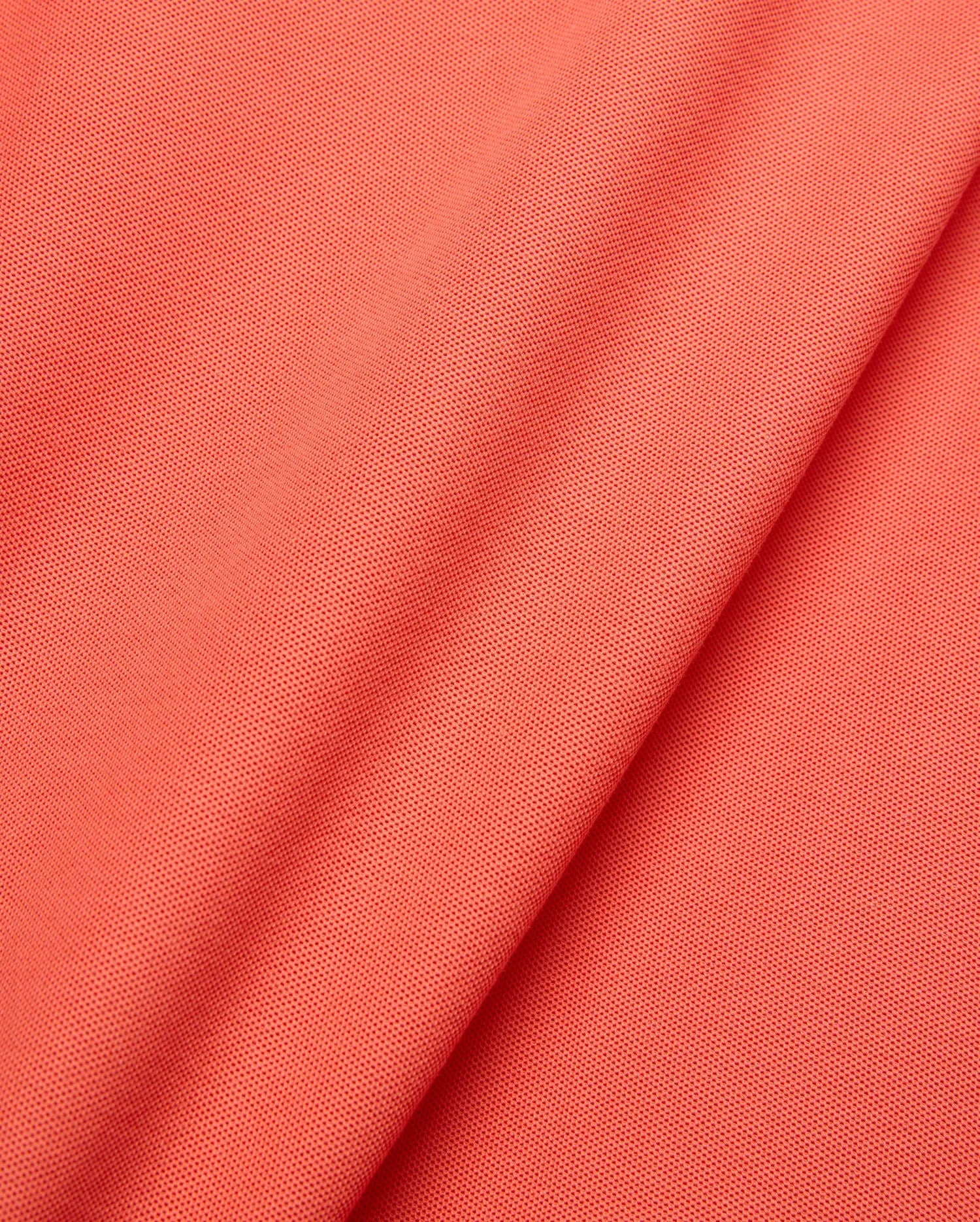 Mens Brad Pique Polo in vibrant coral, showcasing a refined pique knit texture. This premium Psycho Bunny polo features the iconic embroidered bunny skull logo on the chest. (6)