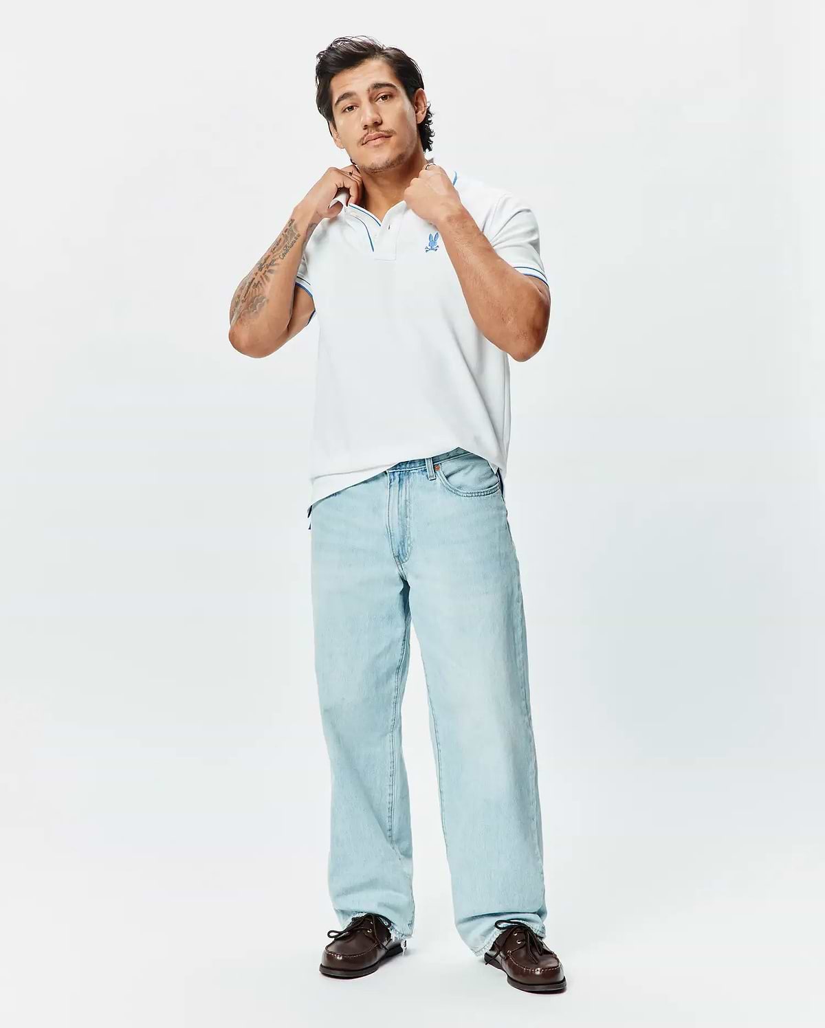 Mens Brad Pique Polo, a classic fit white pique polo with blue tipping on the collar and cuffs, featuring an embroidered blue Psycho Bunny skull logo on the left chest.