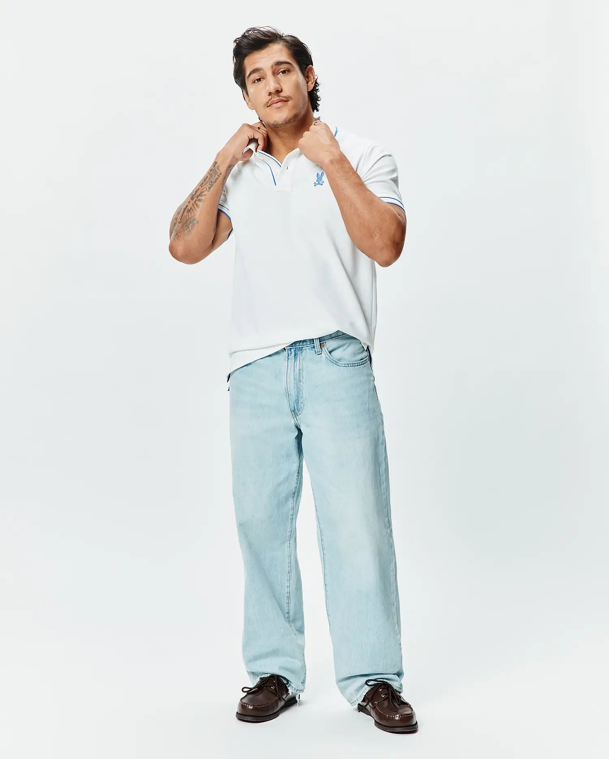 Mens Brad Pique Polo, a classic fit white pique polo with blue tipping on the collar and cuffs, featuring an embroidered blue Psycho Bunny skull logo on the left chest.