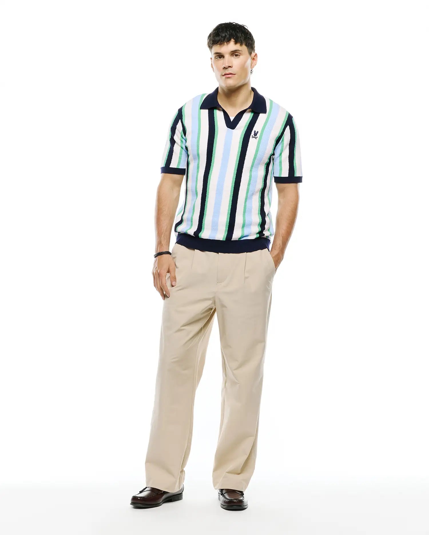 Mens Wren Stripe Knit Polo, a classic fit knit polo with white, light blue, green, and navy vertical stripes, navy V-neck collar, ribbed cuffs, and hem, featuring a small embroidered Psycho Bunny skull logo on the left chest. (5)