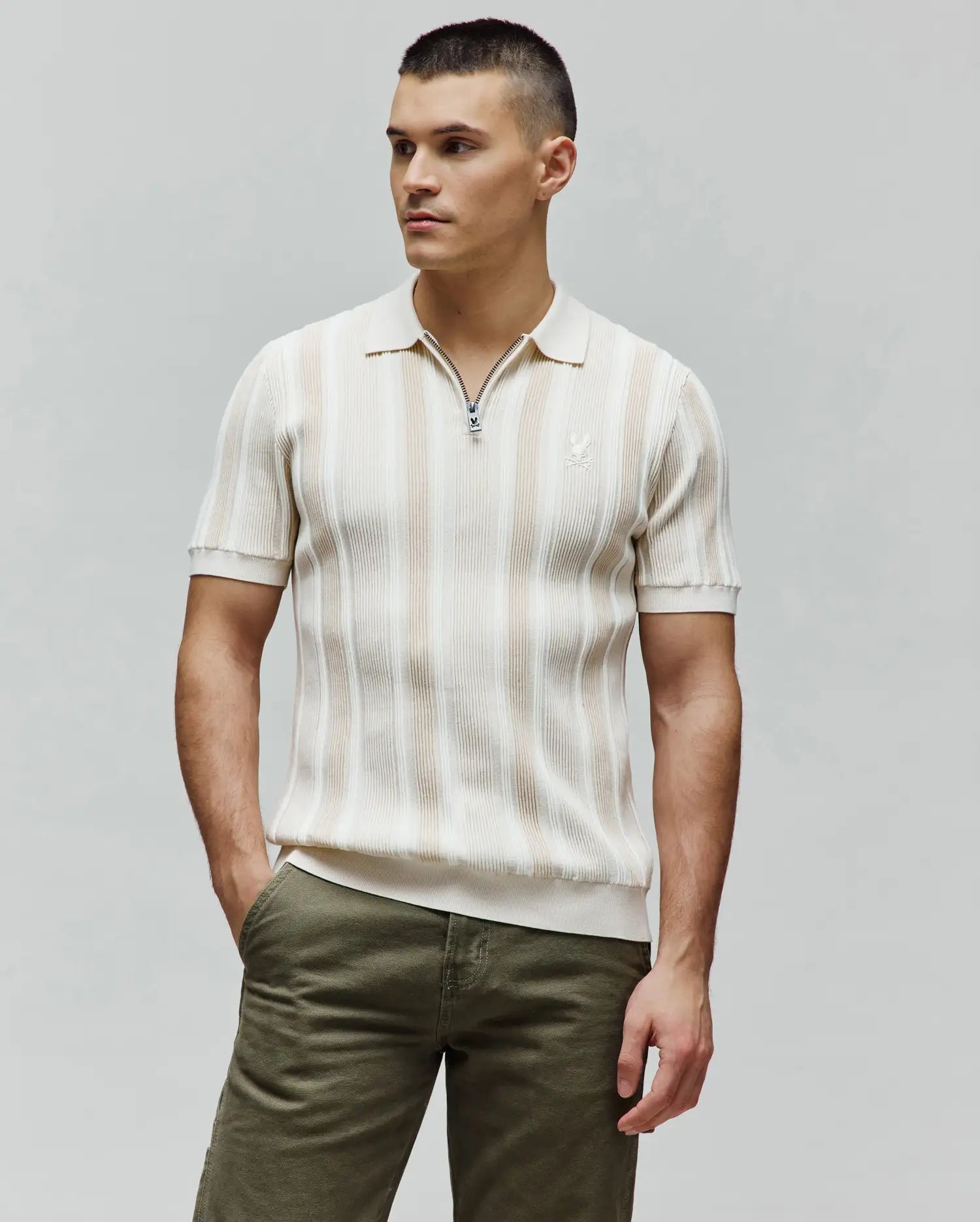 Mens Cliff Knit Zip Polo, cream and beige striped ribbed knit, classic fit, with a Psycho Bunny skull zipper pull and embroidered logo on the left chest.