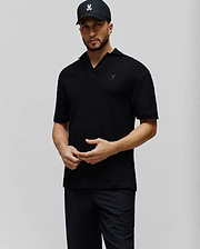 Mens Garen Knit Polo. Black, relaxed fit, textured knit polo with an open collar and a small, embroidered dark grey Psycho Bunny skull logo on the left chest. (1)