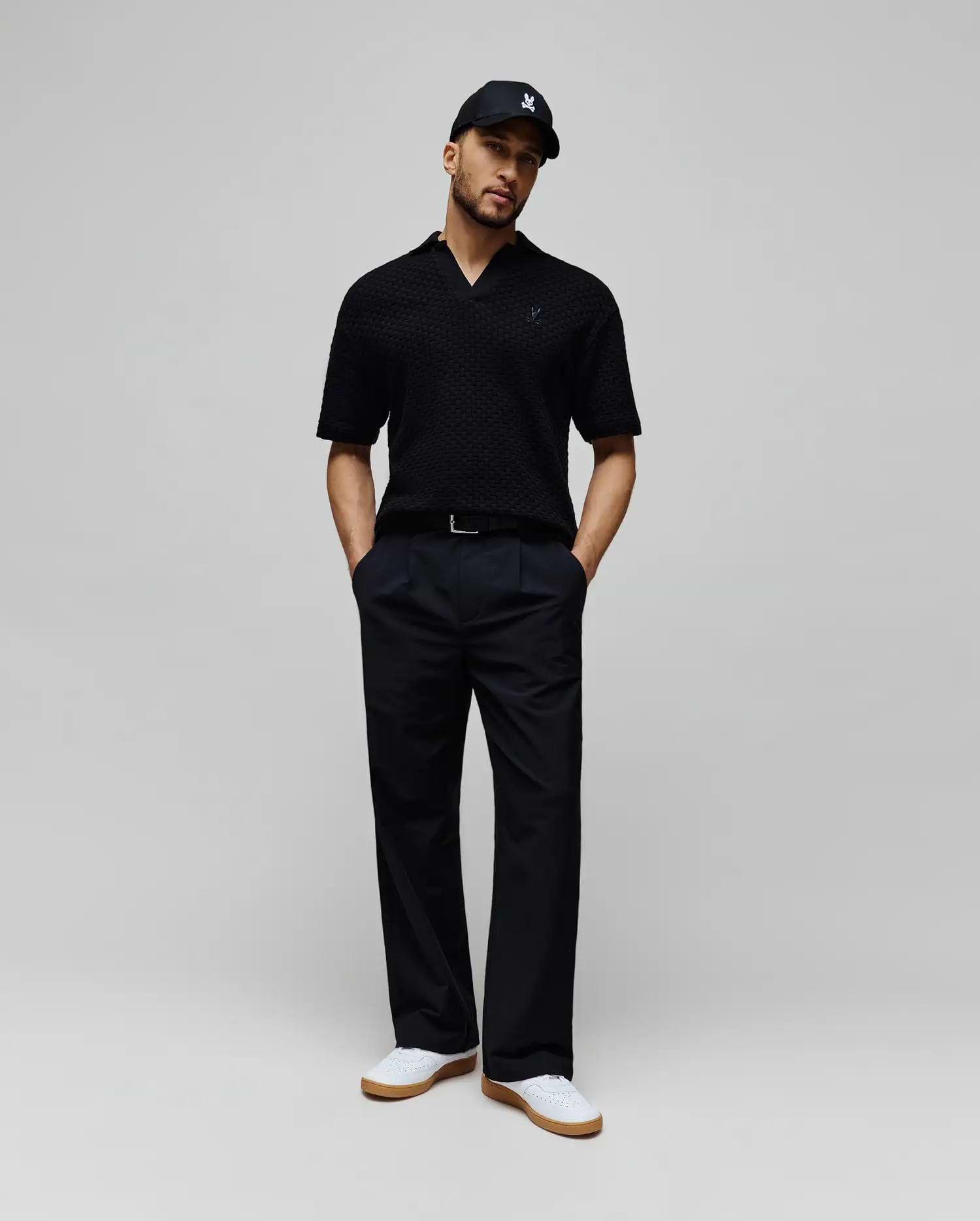 Mens Garen Knit Polo in black, featuring a textured knit fabric, open collar, and a small dark blue embroidered Psycho Bunny skull logo on the left chest for a classic fit. (3)