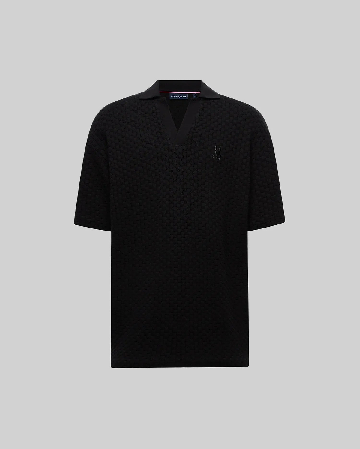 Mens Garen Knit Polo, a black relaxed fit textured knit polo with an open V-neck collar and a small embroidered black Psycho Bunny skull logo on the left chest. (4)