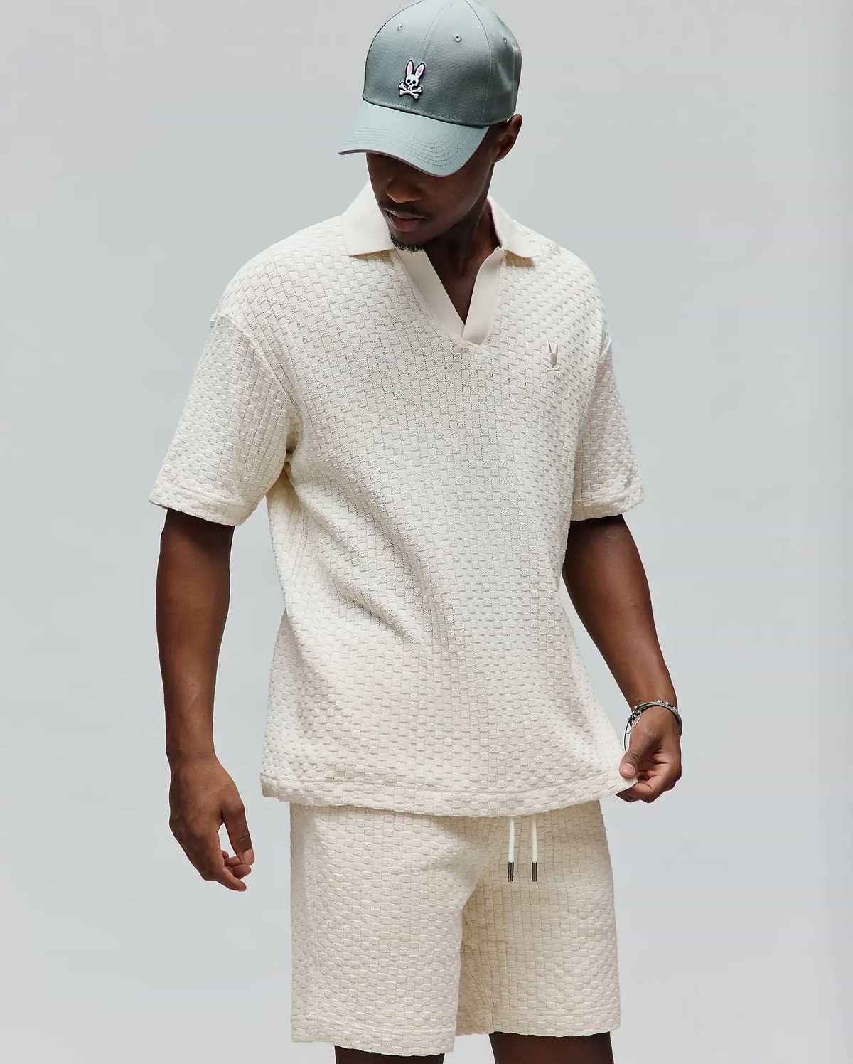 Mens Garen Knit Polo in cream, featuring a relaxed fit, textured basketweave knit fabric, an open resort collar, and a small embroidered Psycho Bunny skull logo on the left chest. (3)