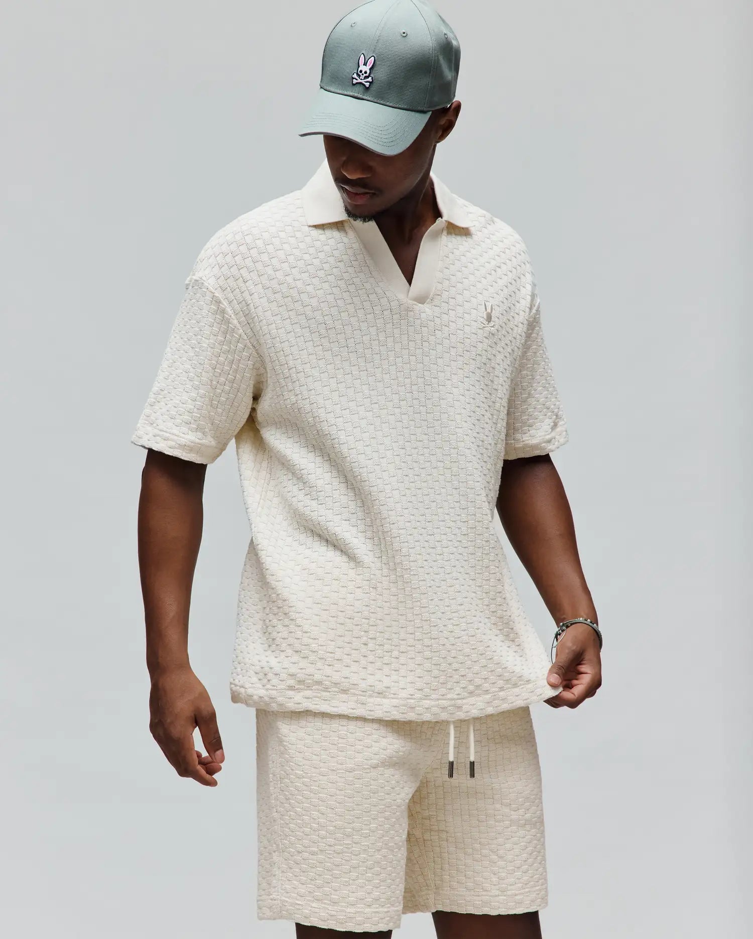 Mens Garen Knit Polo in cream, featuring a relaxed fit, textured basketweave knit fabric, an open resort collar, and a small embroidered Psycho Bunny skull logo on the left chest. (3)