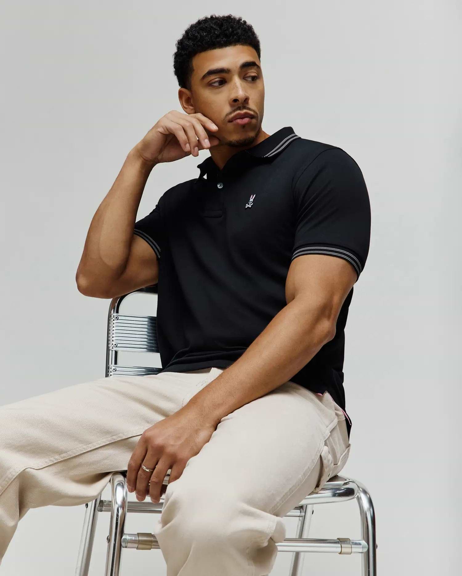Mens Kenyon Pique Polo in classic fit black pique, featuring a two-button placket, white/silver tipped collar and cuffs, and a small embroidered pink/white/black Psycho Bunny skull logo on the left chest. (3)
