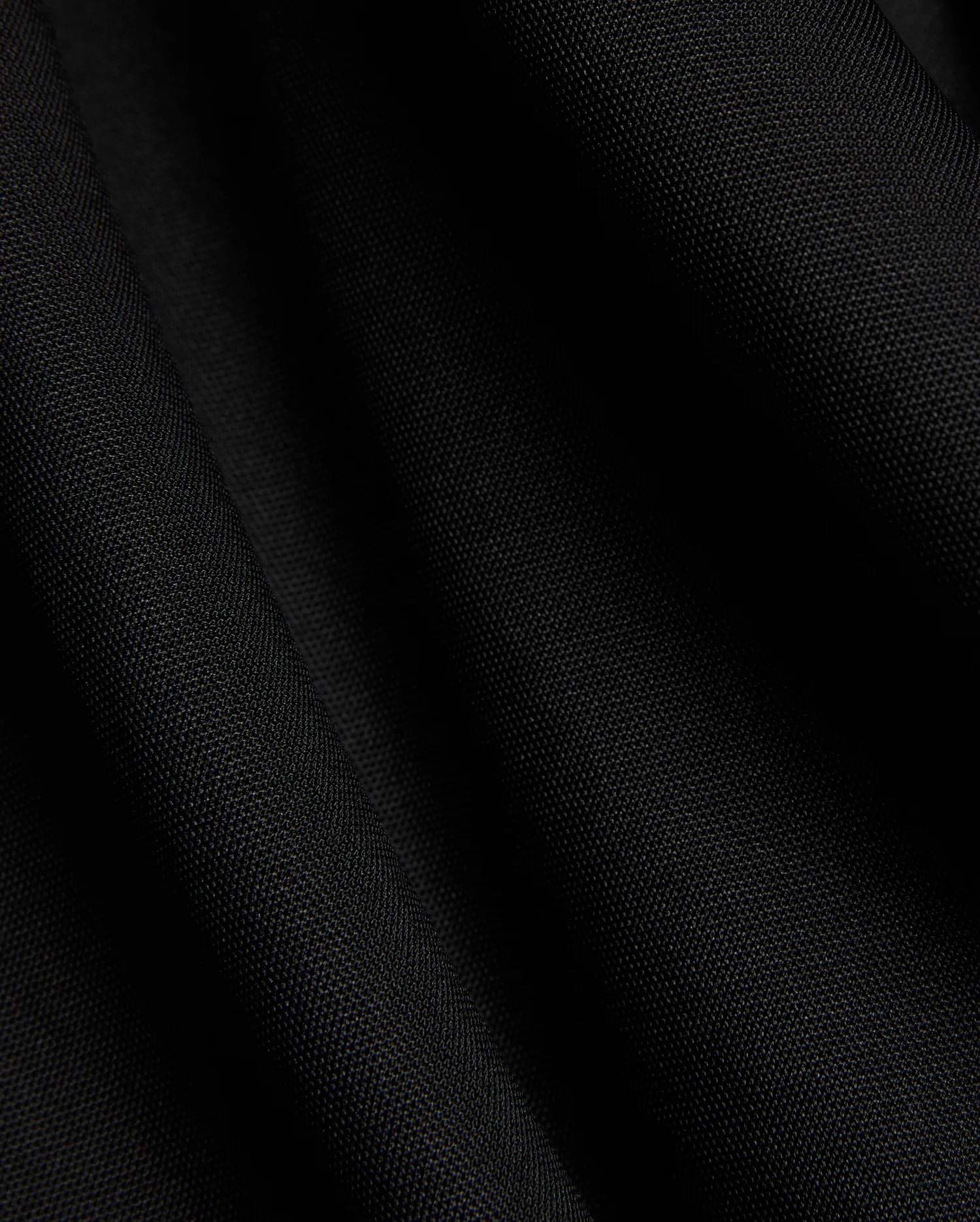 Mens Odin Zip Sport Polo in a rich black, featuring a visible premium pique knit fabric texture, characteristic of Psycho Bunny's refined streetwear style.