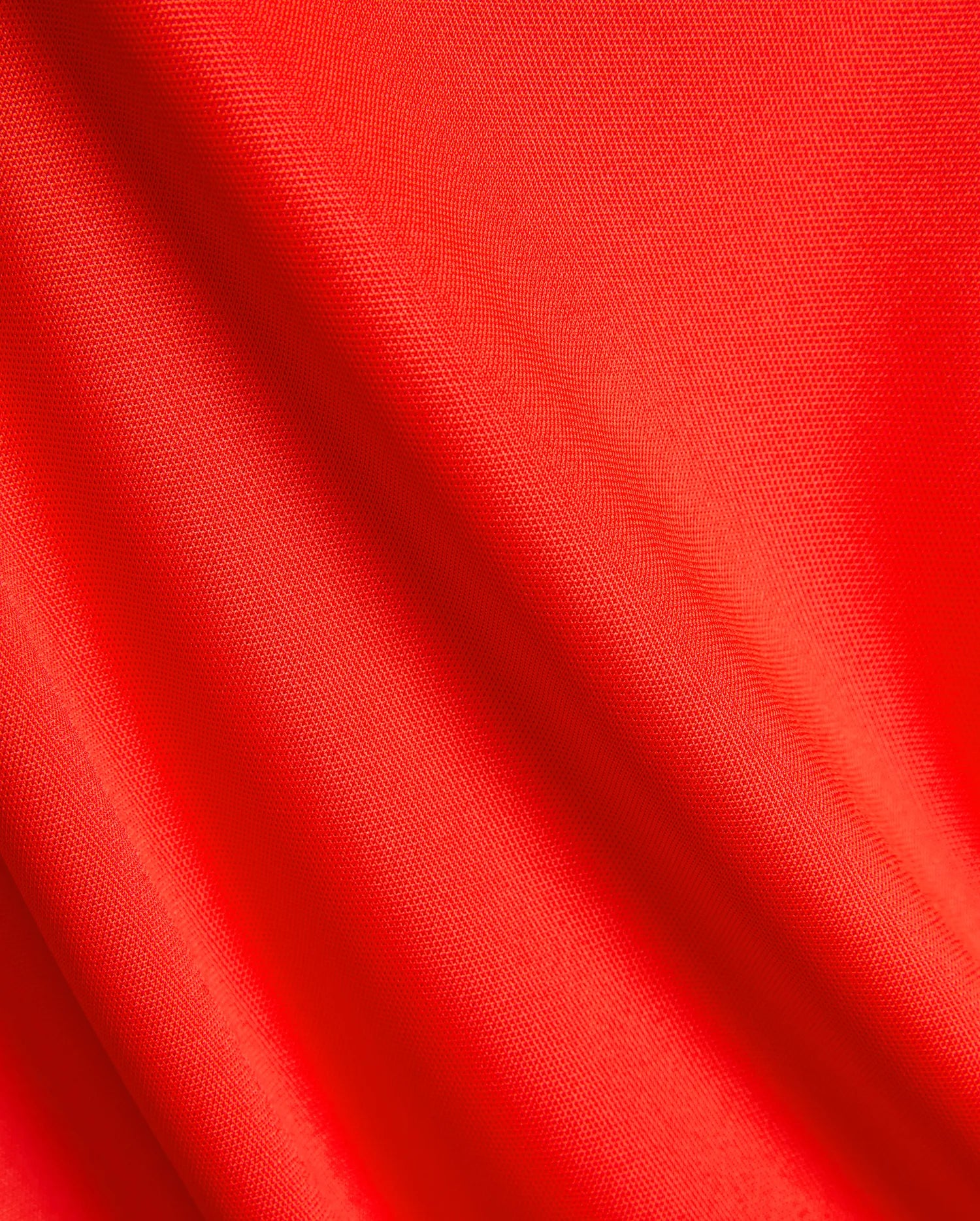 Vibrant red pique knit fabric for the Mens Odin Zip Sport Polo, a premium Psycho Bunny piece, showcasing its distinctive textured weave, ideal for refined streetwear.