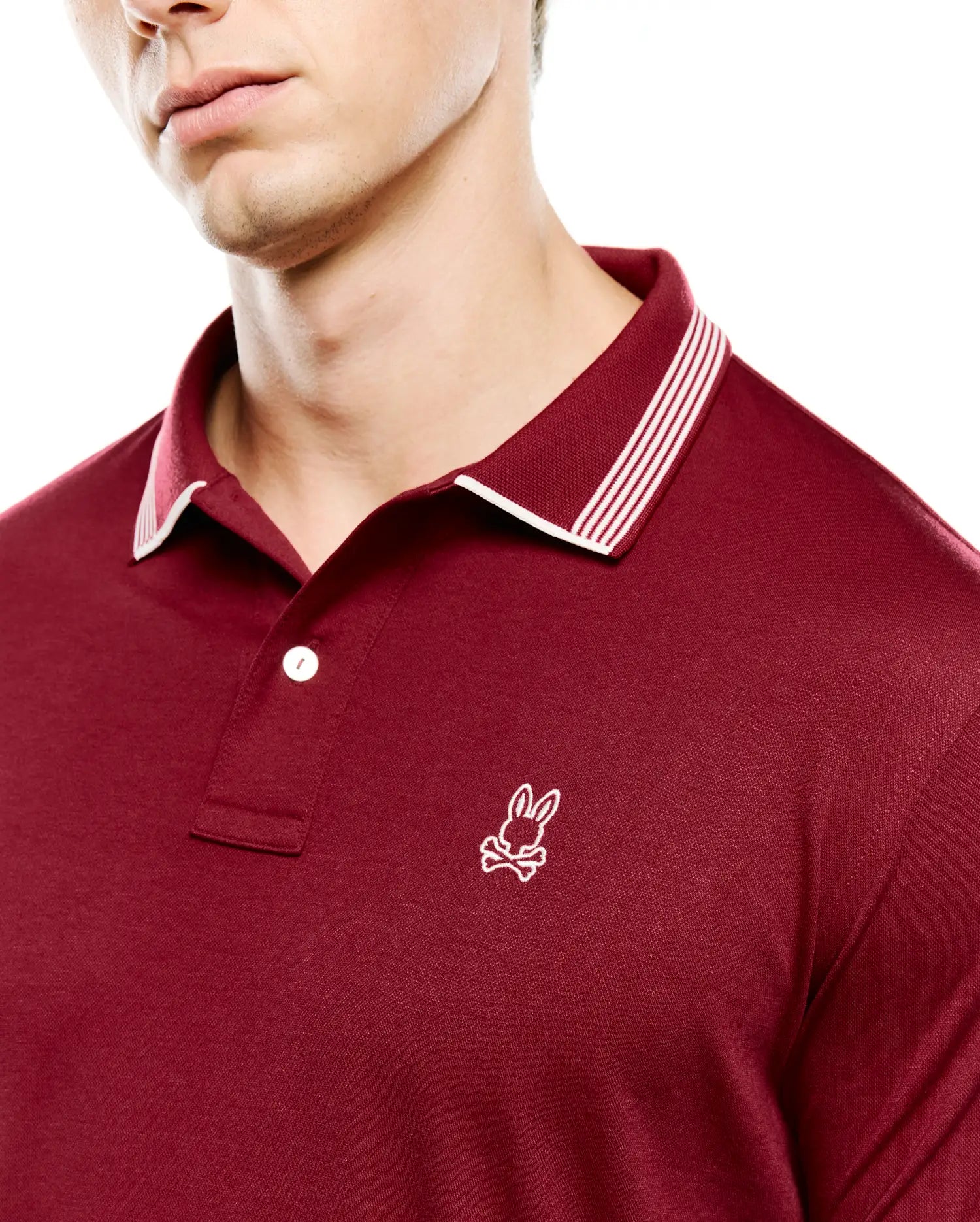 Mens Timmy Interlock Polo in deep maroon, featuring a smooth interlock knit fabric, classic fit, ribbed collar with white tipping and three white stripes, and a small white embroidered Psycho Bunny skull logo on the left chest.
