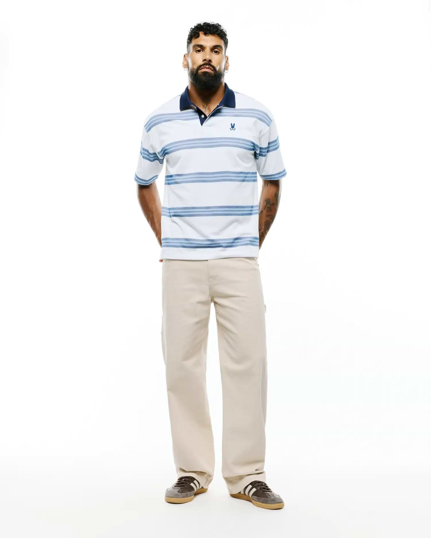 Mens Drew Striped Pique Polo, a classic fit white pique polo with navy collar, light blue horizontal stripes, and a small embroidered Psycho Bunny skull logo on the left chest. (3)
