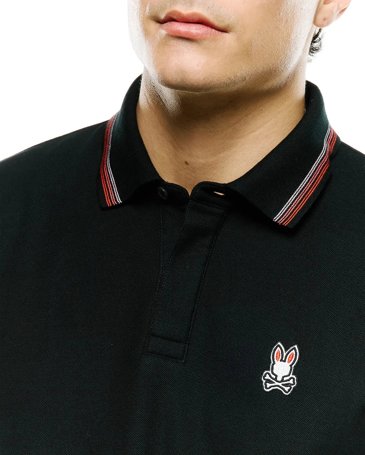 Black Mens Jaydon Pique Polo with classic fit, pique texture, and a small embroidered Psycho Bunny skull logo on the left chest. Collar features red and white stripe accents. (2)