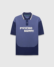 Mens Kelly Oversized Polo, an oversized two-tone blue jersey polo with medium blue and navy color-block, white-striped navy collar, large white embroidered PSYCHO BUNNY chest text, and small back neck bunny skull logo. (5)