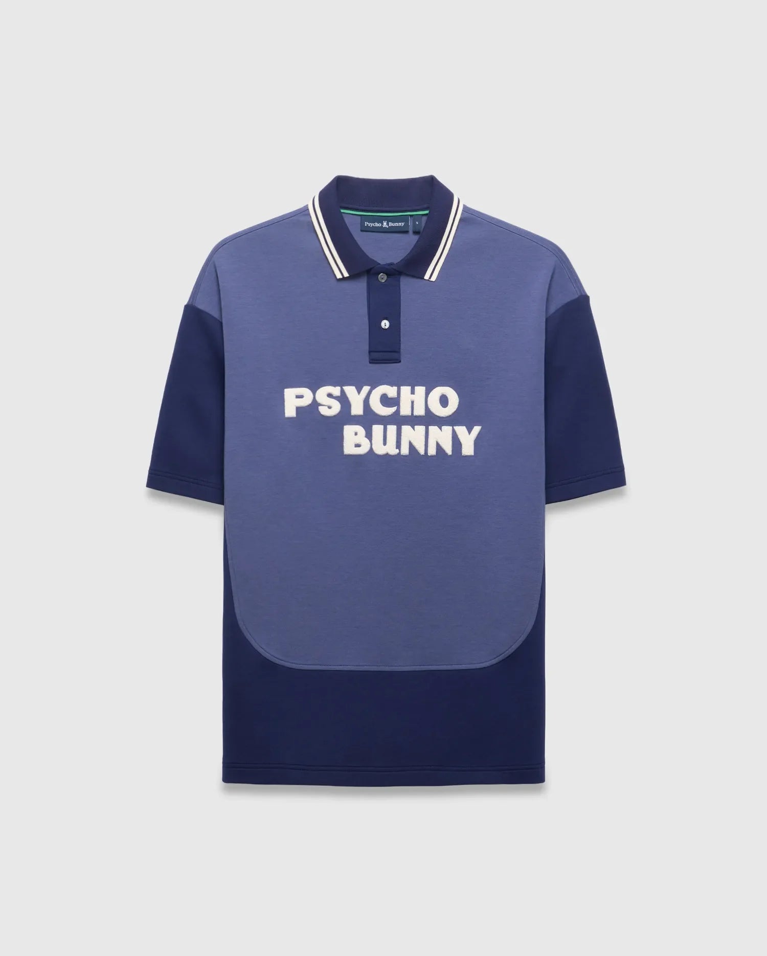 Mens Kelly Oversized Polo, an oversized two-tone blue jersey polo with medium blue and navy color-block, white-striped navy collar, large white embroidered PSYCHO BUNNY chest text, and small back neck bunny skull logo. (5)
