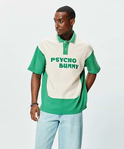 Mens Kelly Oversized Polo, a kelly green and cream color block polo with an oversized fit. Features a soft jersey texture, short sleeves, and large embroidered PSYCHO BUNNY text on the cream chest.