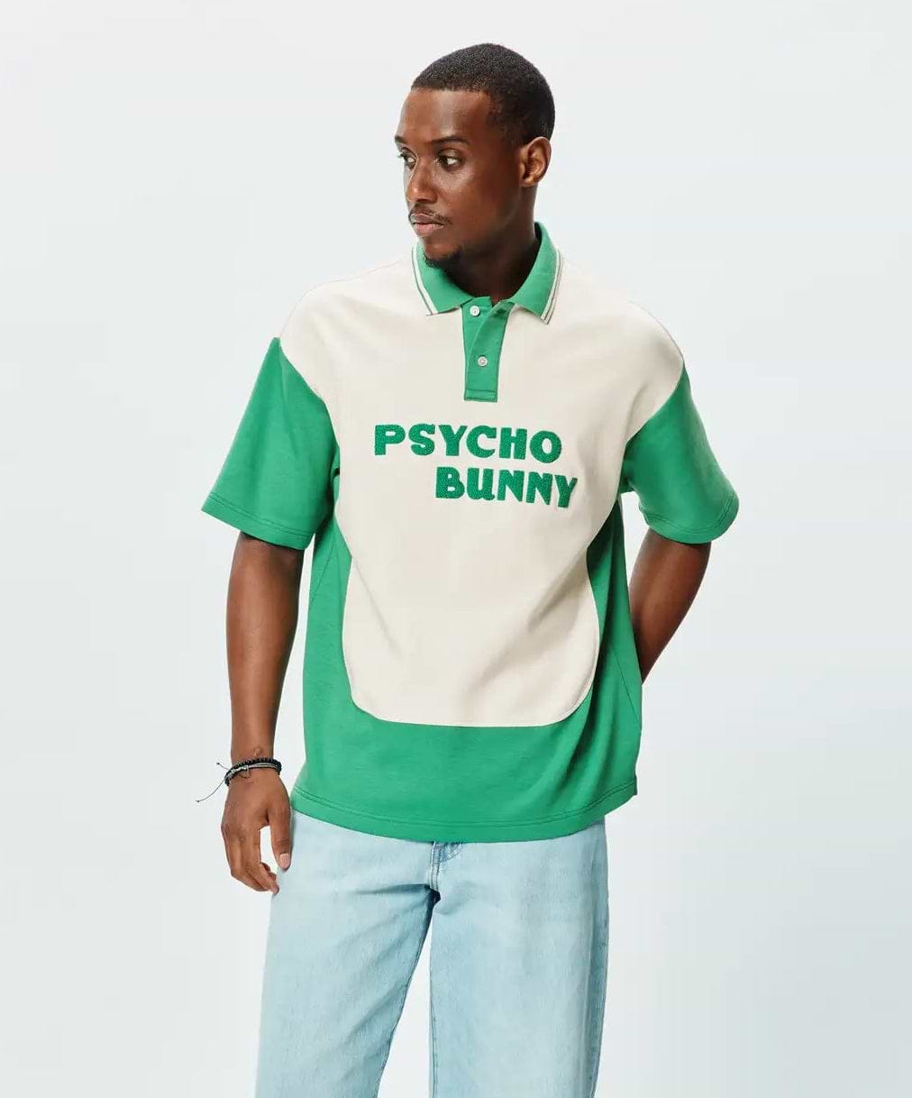 Mens Kelly Oversized Polo, a kelly green and cream color block polo with an oversized fit. Features a soft jersey texture, short sleeves, and large embroidered PSYCHO BUNNY text on the cream chest.