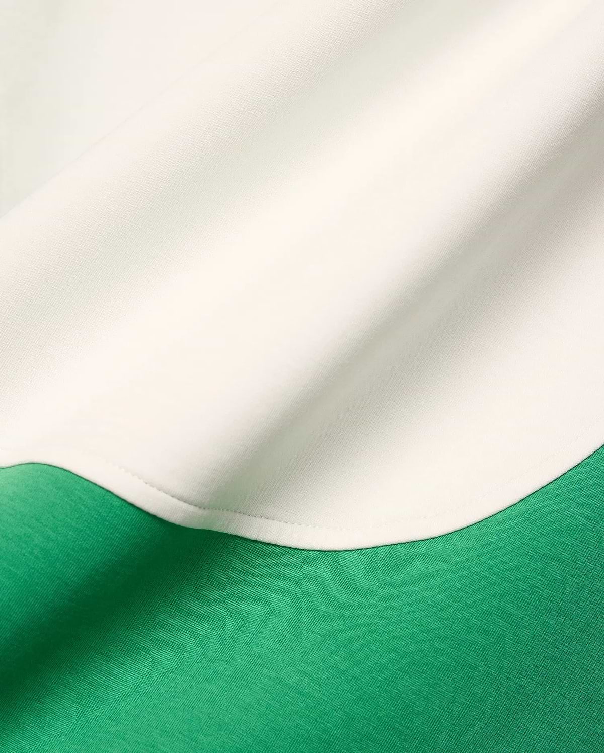 Mens Kelly Oversized Polo in a color block design featuring a vibrant green jersey knit body and a creamy white accent panel with a curved seam.