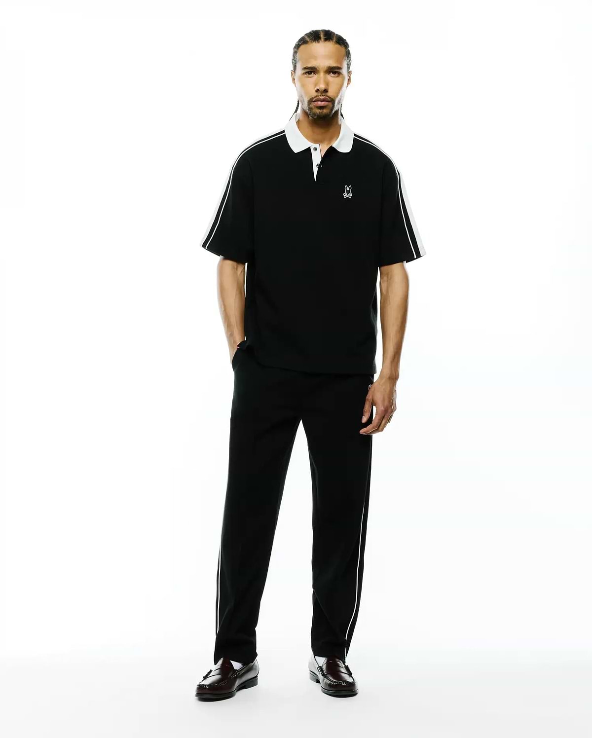 Mens Ceano Relaxed Fit Heavy Pique Polo, black with a crisp white collar, white cuffs, and white piping detail along the shoulders and sleeves, featuring a small embroidered white Psycho Bunny skull logo on the left chest.