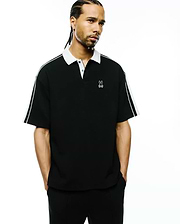 Mens Ceano Relaxed Fit Heavy Pique Polo, black with a crisp white collar, white double stripes on the sleeves, and a white embroidered Psycho Bunny skull logo on the left chest.
