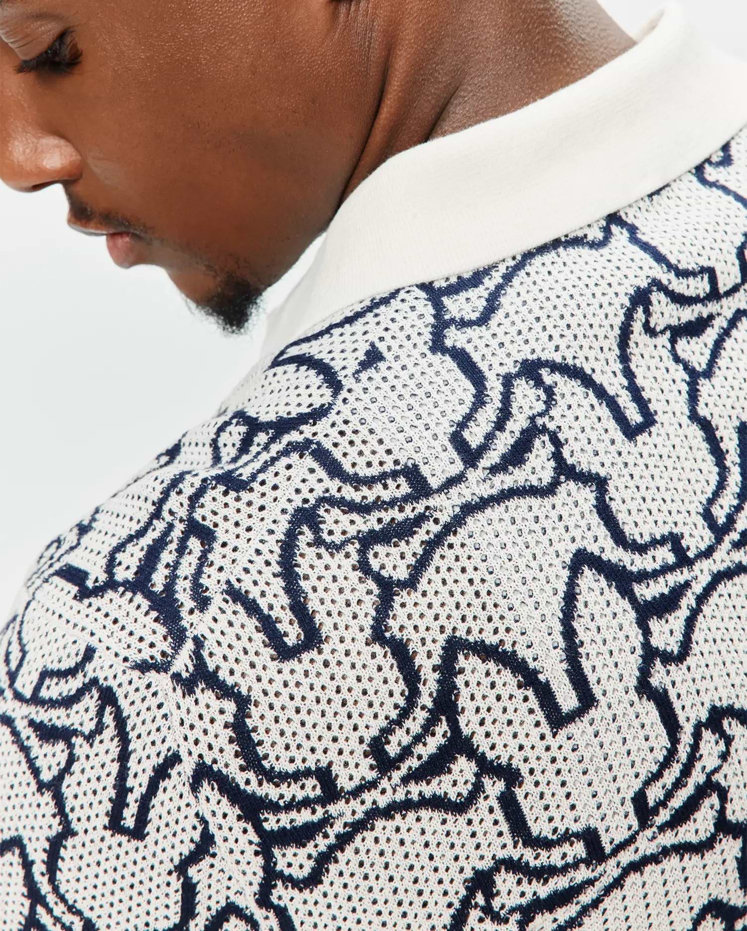 Mens Sidney Oversized Knit Polo in cream with an all-over navy blue abstract bunny skull pattern, featuring a textured open-knit fabric and a solid cream ribbed collar. (3)