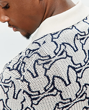 Mens Sidney Oversized Knit Polo in cream with an all-over navy blue abstract bunny skull pattern, featuring a textured open-knit fabric and a solid cream ribbed collar. (3)