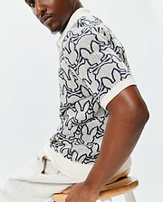 Mens Sidney Oversized Knit Polo, a cream open-weave knit polo featuring an all-over navy blue Psycho Bunny skull pattern and a relaxed, oversized fit. (2)