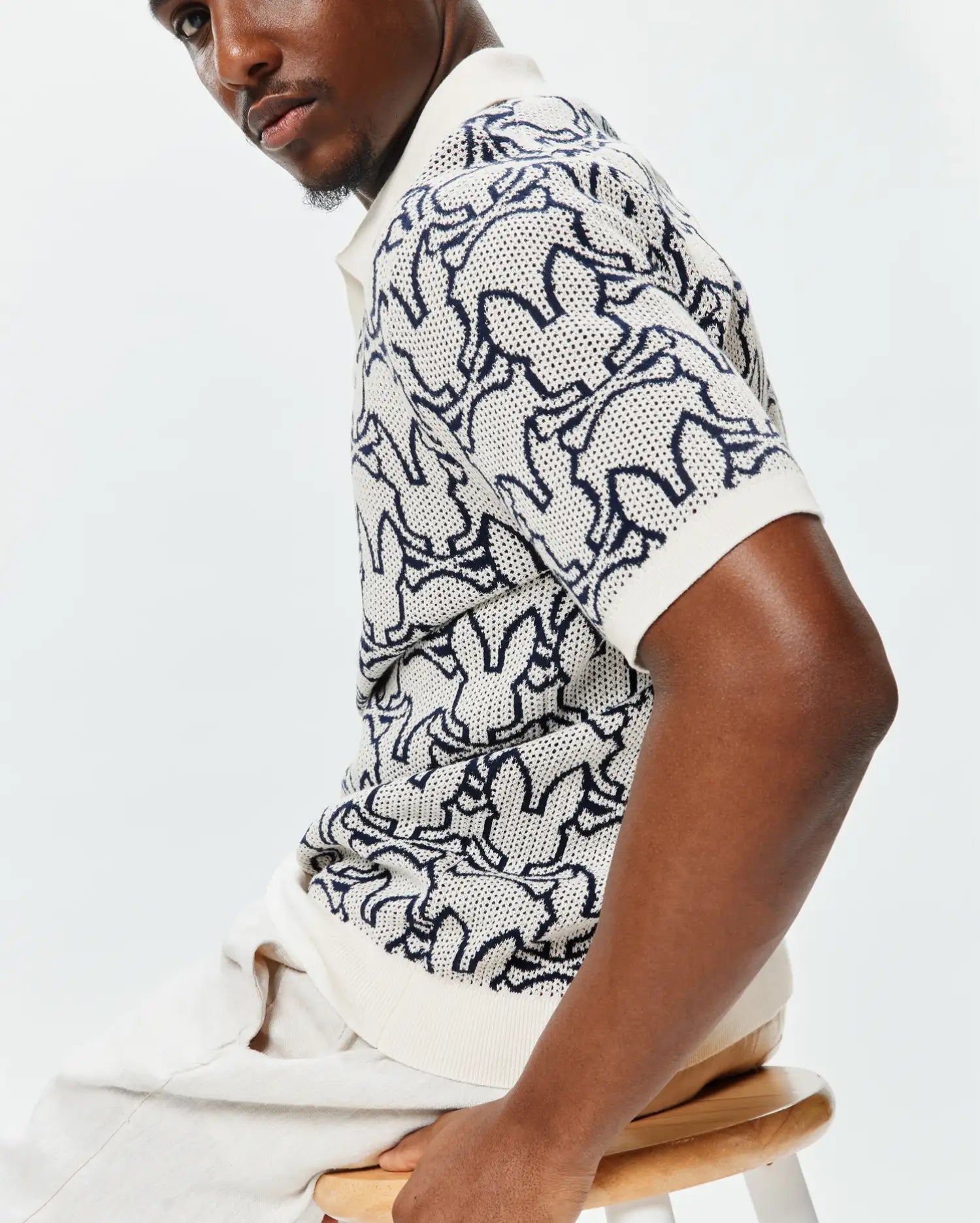 Mens Sidney Oversized Knit Polo, a cream open-weave knit polo featuring an all-over navy blue Psycho Bunny skull pattern and a relaxed, oversized fit. (2)