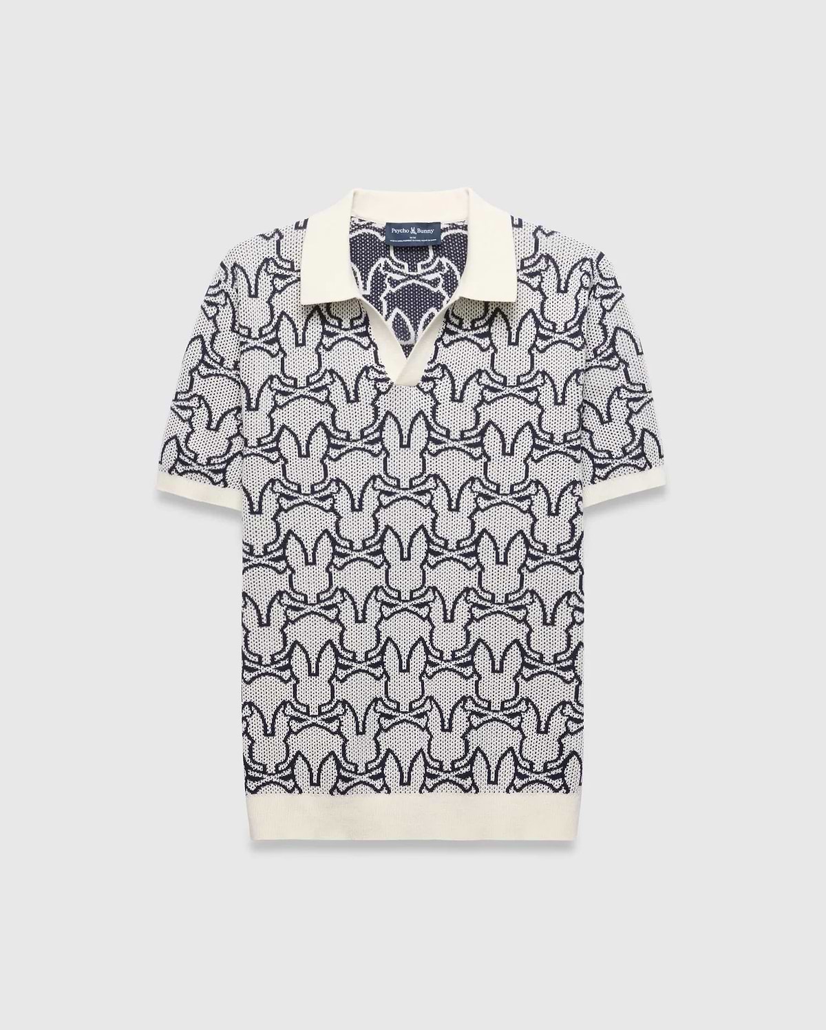 Mens Sidney Oversized Knit Polo, a cream and navy blue jacquard knit polo featuring an all-over Psycho Bunny skull logo pattern, solid cream collar, cuffs, and an oversized fit. (4)