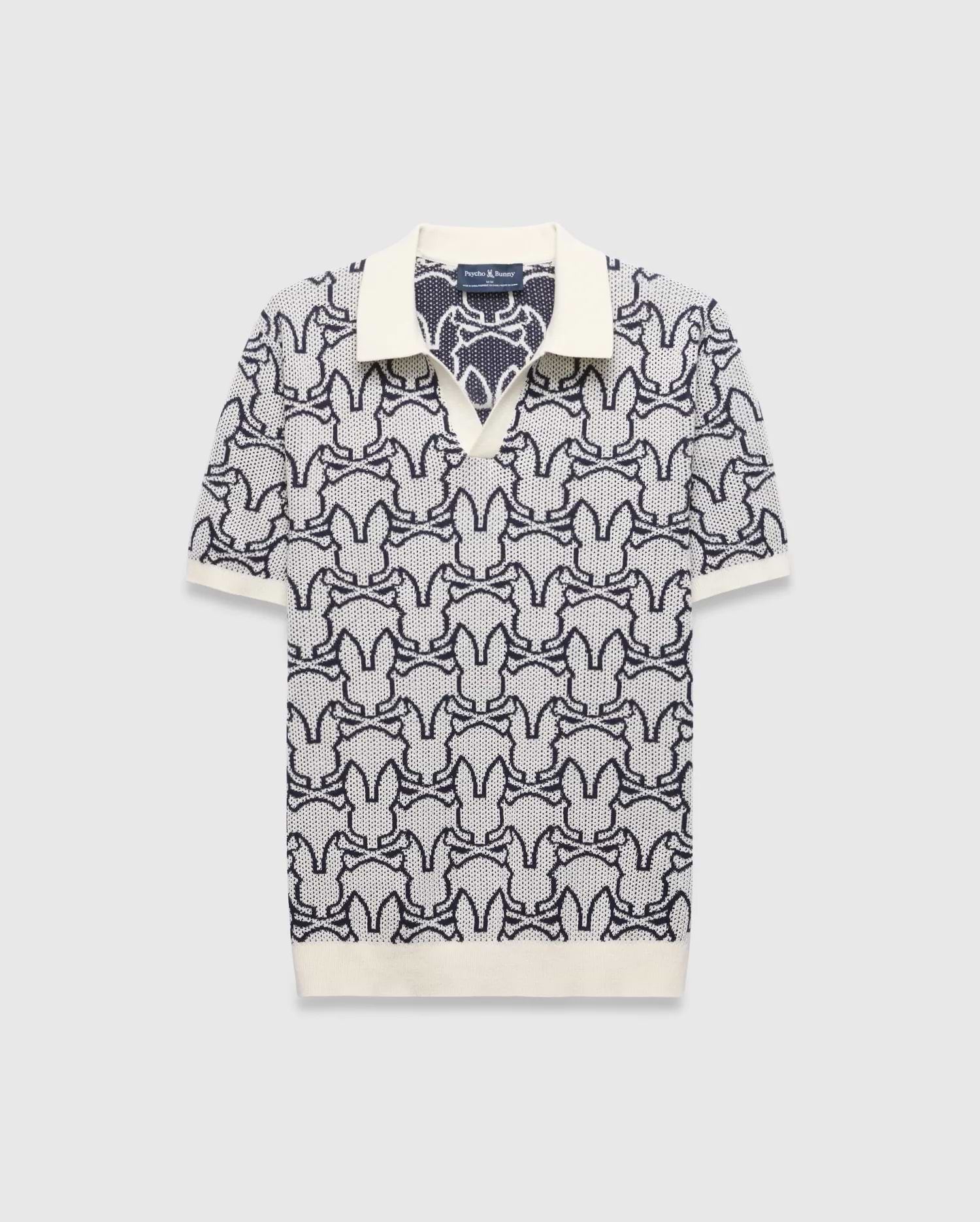 Mens Sidney Oversized Knit Polo, a cream and navy blue jacquard knit polo featuring an all-over Psycho Bunny skull logo pattern, solid cream collar, cuffs, and an oversized fit. (4)