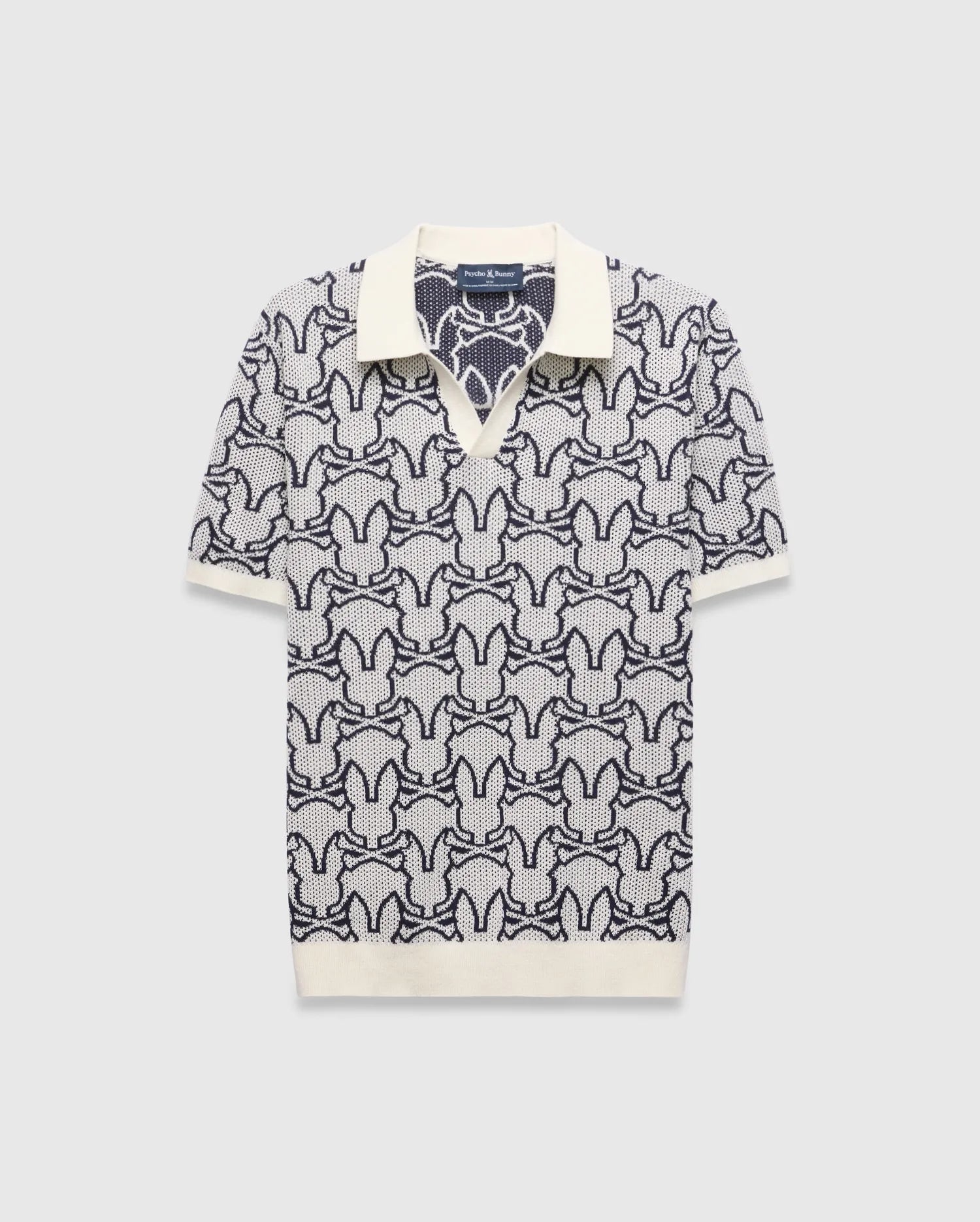 Mens Sidney Oversized Knit Polo, a cream and navy blue jacquard knit polo featuring an all-over Psycho Bunny skull logo pattern, solid cream collar, cuffs, and an oversized fit. (4)