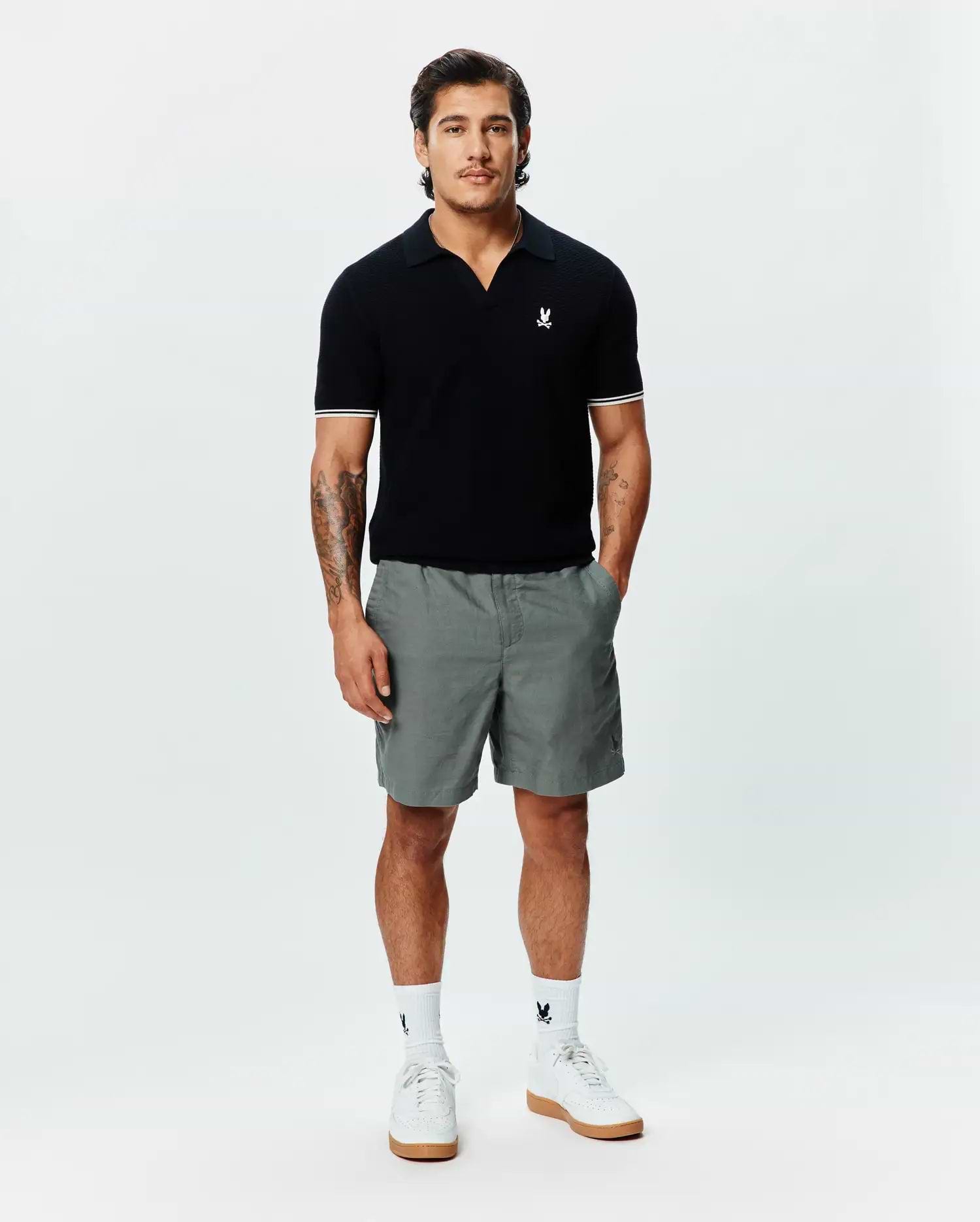 Black MENS SELBY KNIT POLO, classic fit, with an open collar, fine knit texture, white double-striped sleeve cuffs, and a small embroidered white Psycho Bunny skull logo on the left chest. (3)