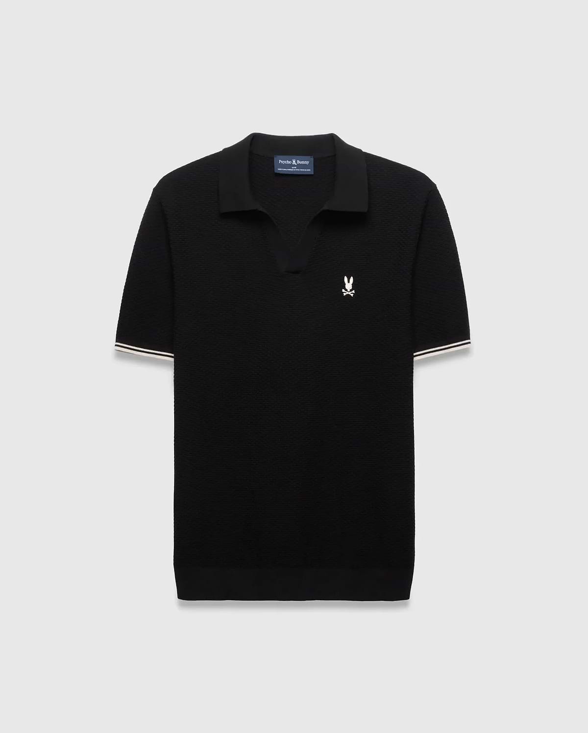 Black Mens Selby Knit Polo featuring a textured knit, classic fit, v-neck collar, and ribbed cuffs with white and cream double stripes. A small white embroidered Psycho Bunny skull logo adorns the left chest. (4)