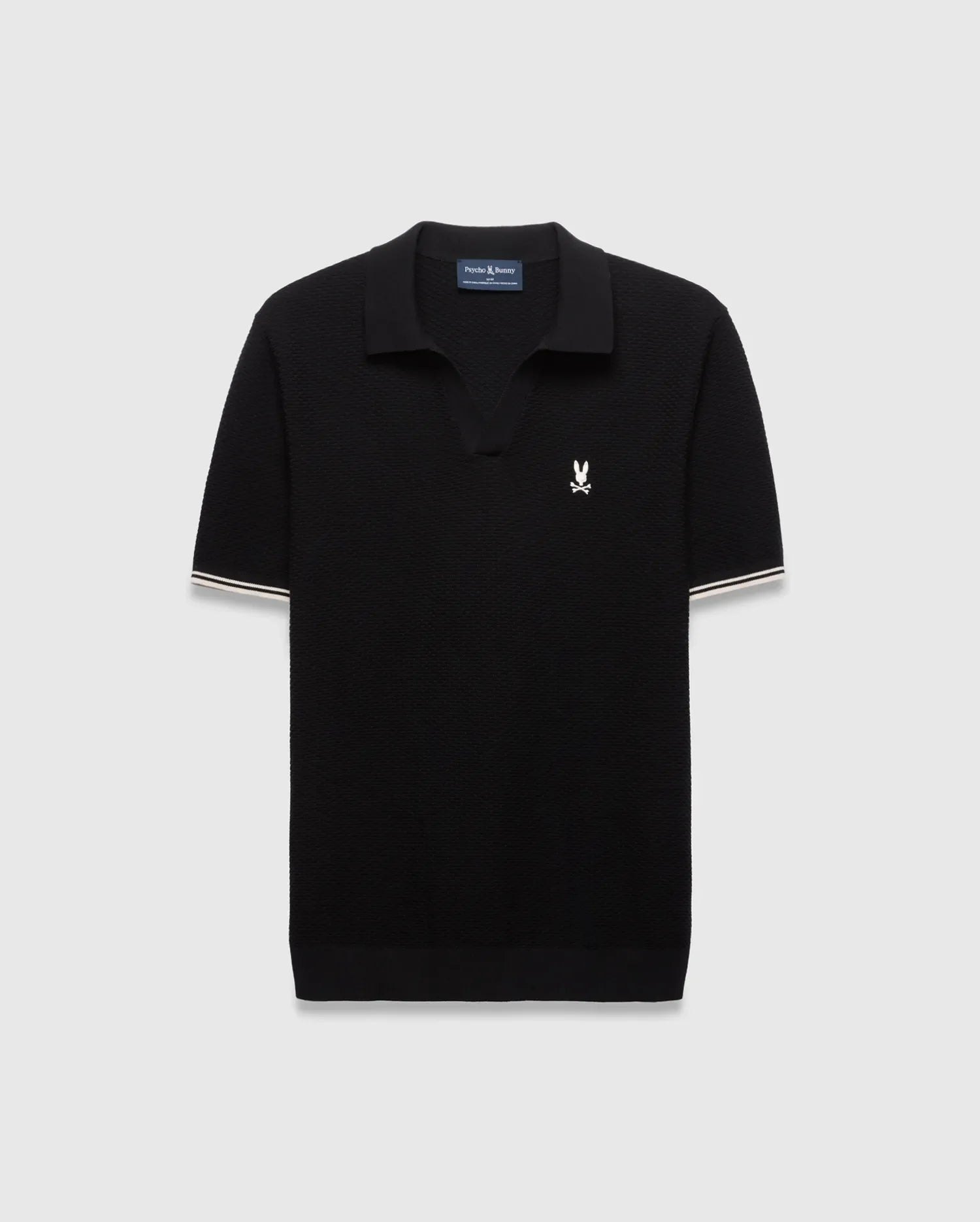 Black Mens Selby Knit Polo featuring a textured knit, classic fit, v-neck collar, and ribbed cuffs with white and cream double stripes. A small white embroidered Psycho Bunny skull logo adorns the left chest. (4)