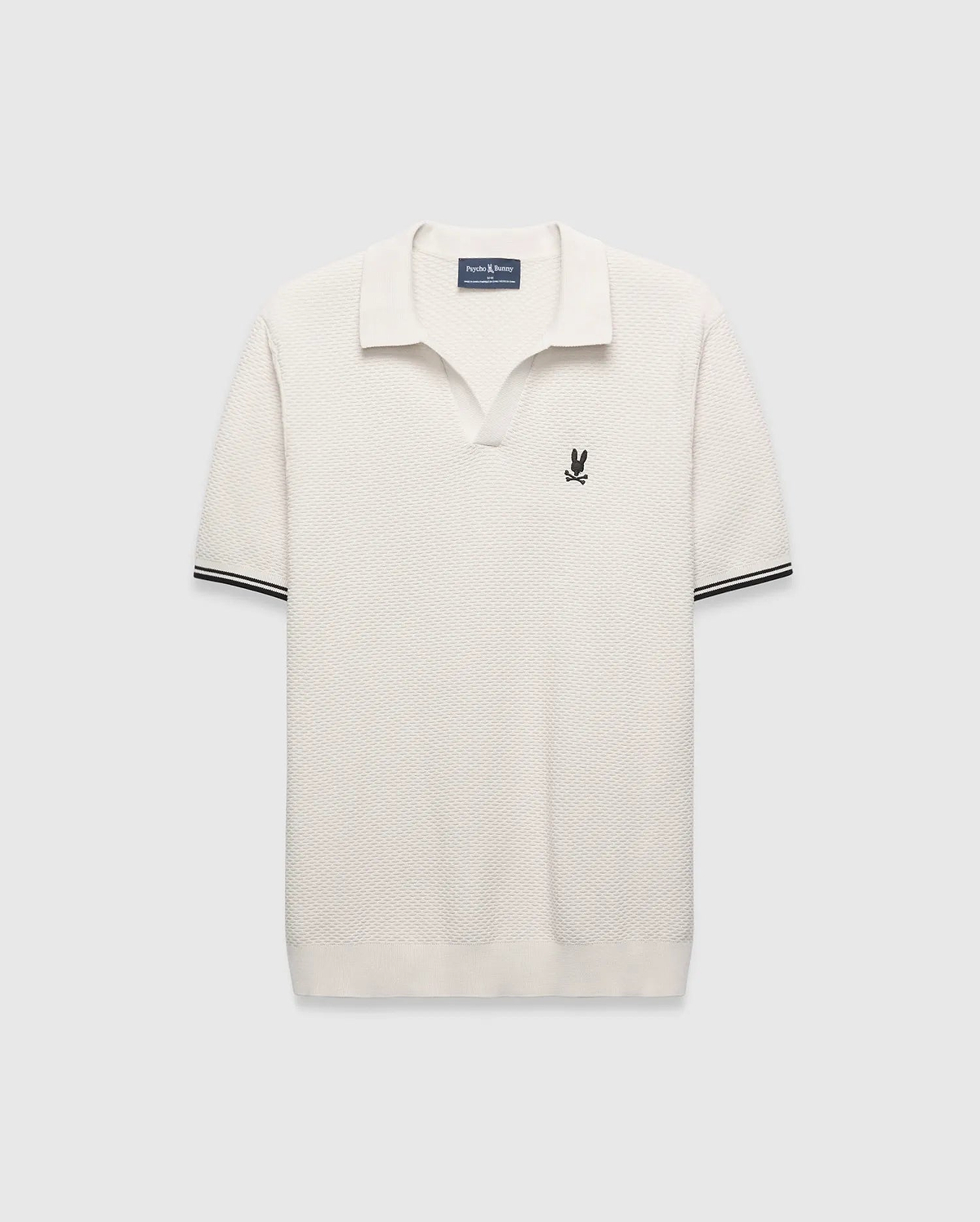 Cream Mens Selby Knit Polo featuring a unique textured knit fabric, open collar, small black embroidered Psycho Bunny skull logo on the left chest, and ribbed cuffs with black double stripes. (5)