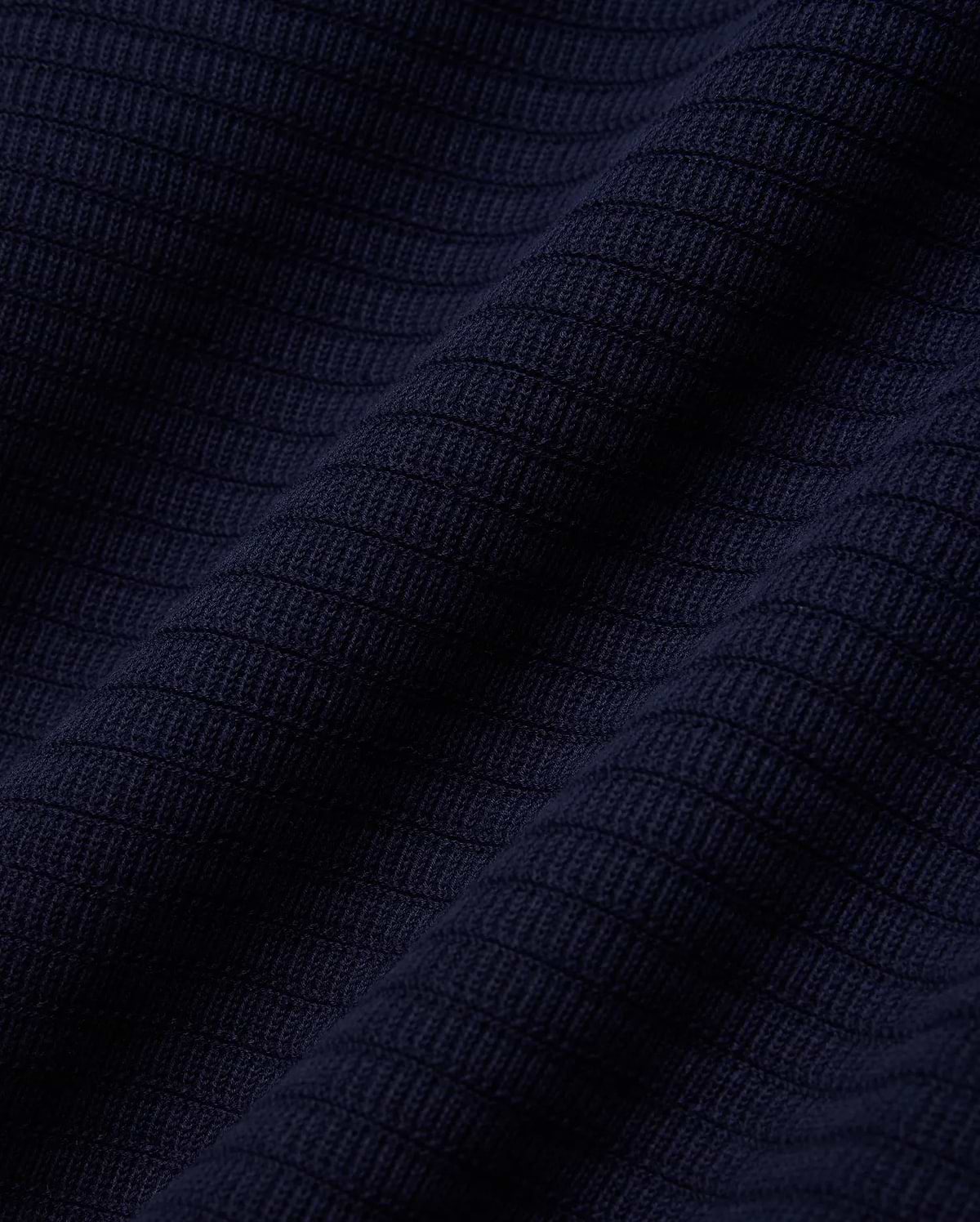 MENS ELOWEN KNIT POLO in deep navy blue, showcasing a finely crafted, horizontally ribbed knit texture with a soft, luxurious feel, characteristic of premium Psycho Bunny apparel. (5)