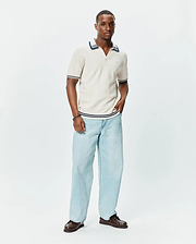 Mens Elowen Knit Polo in cream, featuring a ribbed texture, V-neck, and navy blue stripe accents on the collar, cuffs, and hem, with a small embroidered Psycho Bunny logo on the chest. (3)
