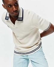 Mens Elowen Knit Polo in cream, featuring a ribbed knit texture, navy and white striped collar, cuffs, and hem, with a small embroidered Psycho Bunny skull logo on the left chest. (1)