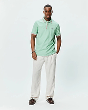 Mens Faye Pique Polo in mint green, a classic fit pique knit with ribbed collar and cuffs featuring red and white tipping, and a small embroidered Psycho Bunny skull logo on the left chest.