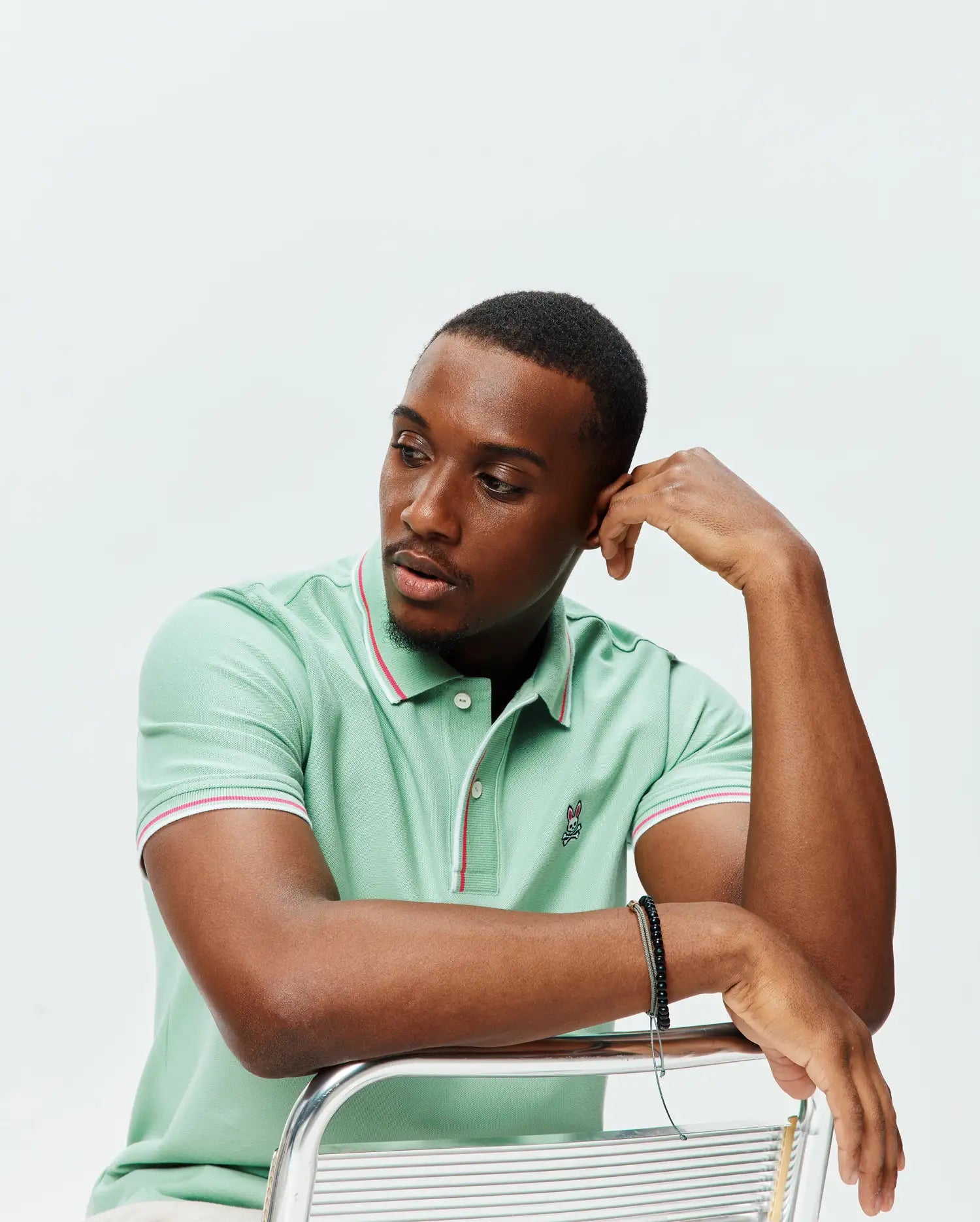 Mens Faye Pique Polo, mint green classic fit with pique texture, featuring white and red striped collar and cuffs, and a small embroidered Psycho Bunny skull logo on the left chest.