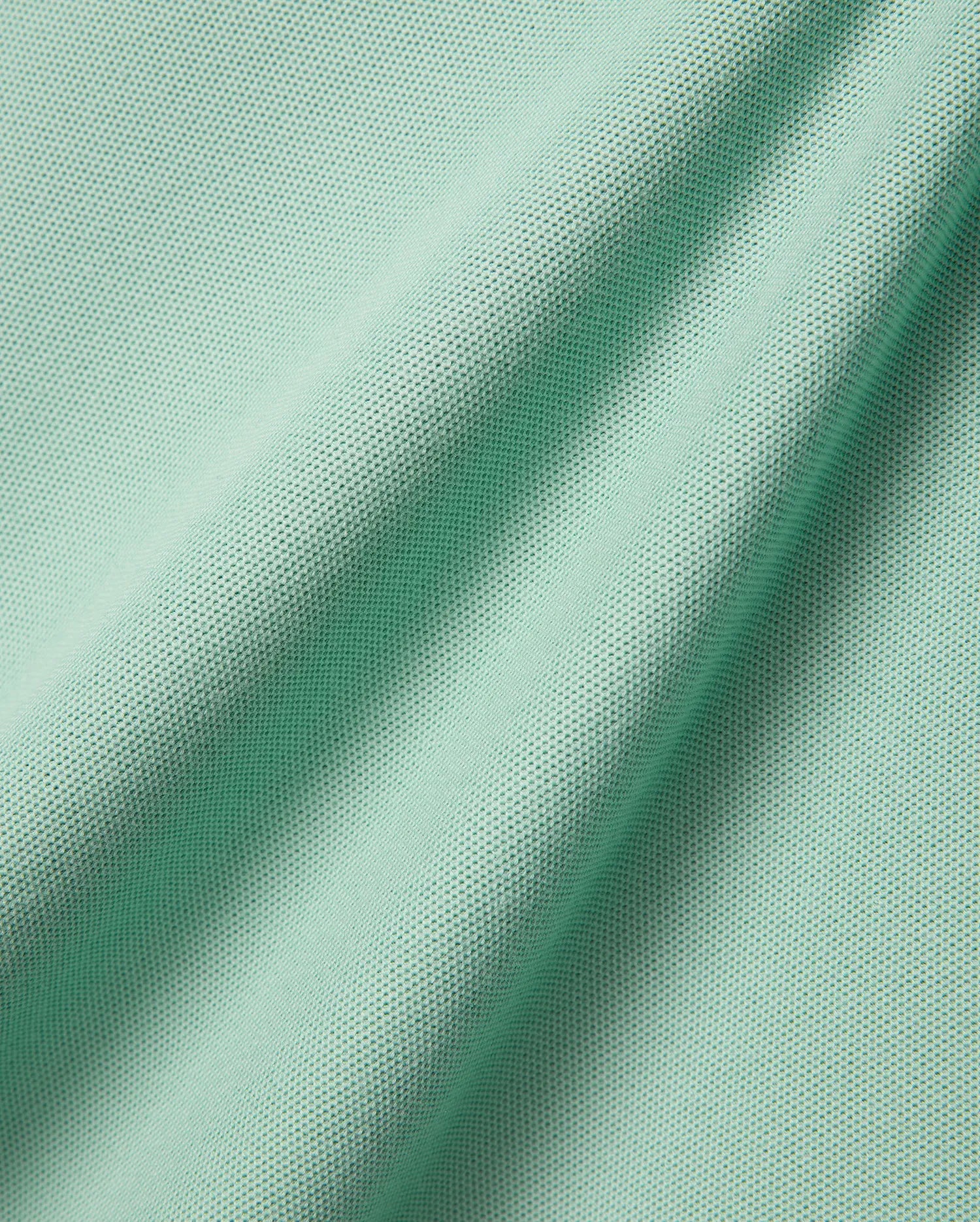 Mens Faye Pique Polo, a luxurious light mint green fabric swatch, showcasing the premium, finely textured pique weave with elegant, natural folds, reflecting refined streetwear quality.