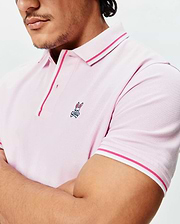 Mens Faye Pique Polo in light pink, featuring a classic fit, pique knit texture, hot pink and white striped collar and cuffs, and a small embroidered Psycho Bunny skull logo on the left chest.