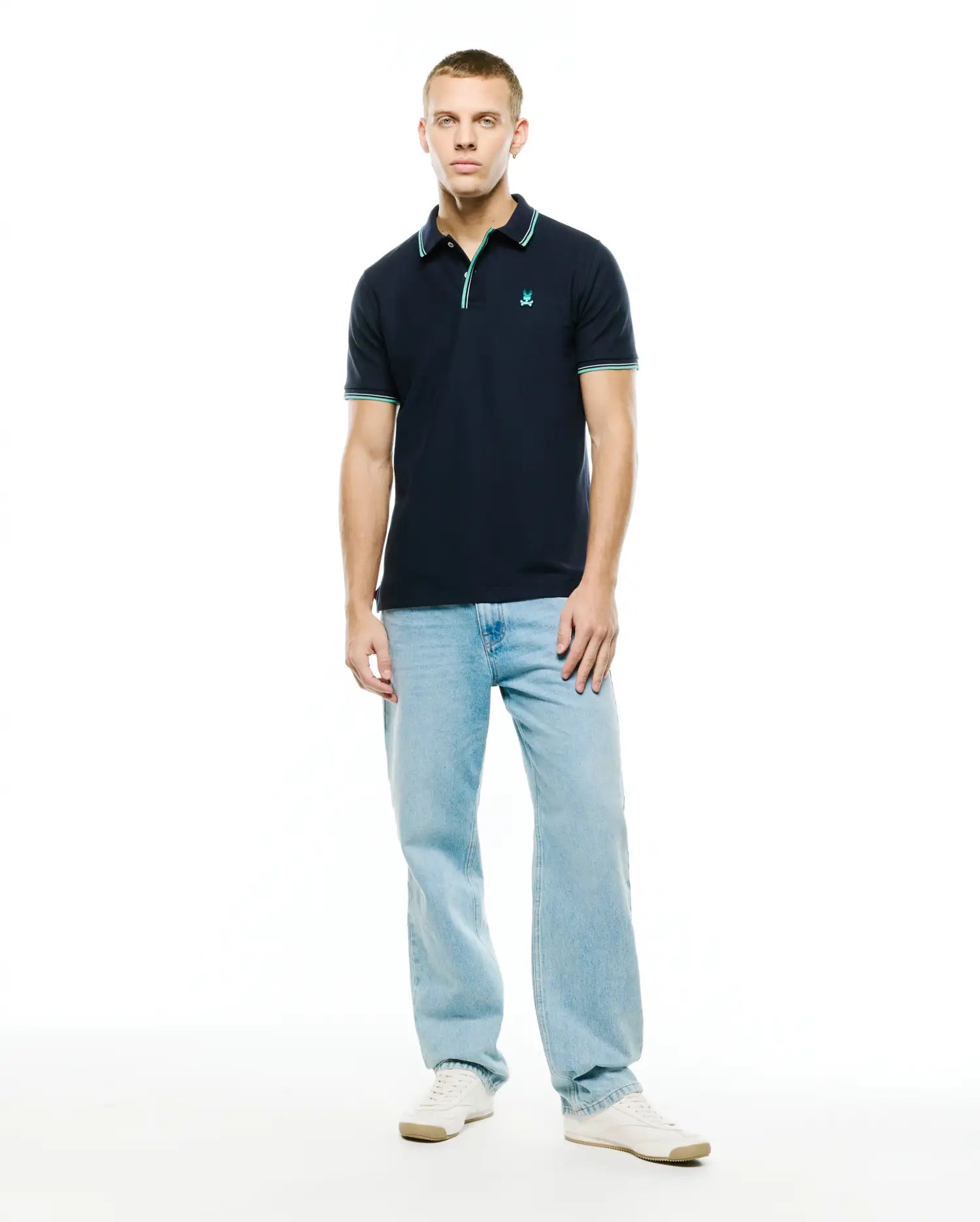 Men's Slade Pique Polo, classic fit navy pique polo shirt with a small embroidered teal Psycho Bunny skull logo on the left chest, featuring ribbed collar and cuffs with teal and white double stripe accents. (4)