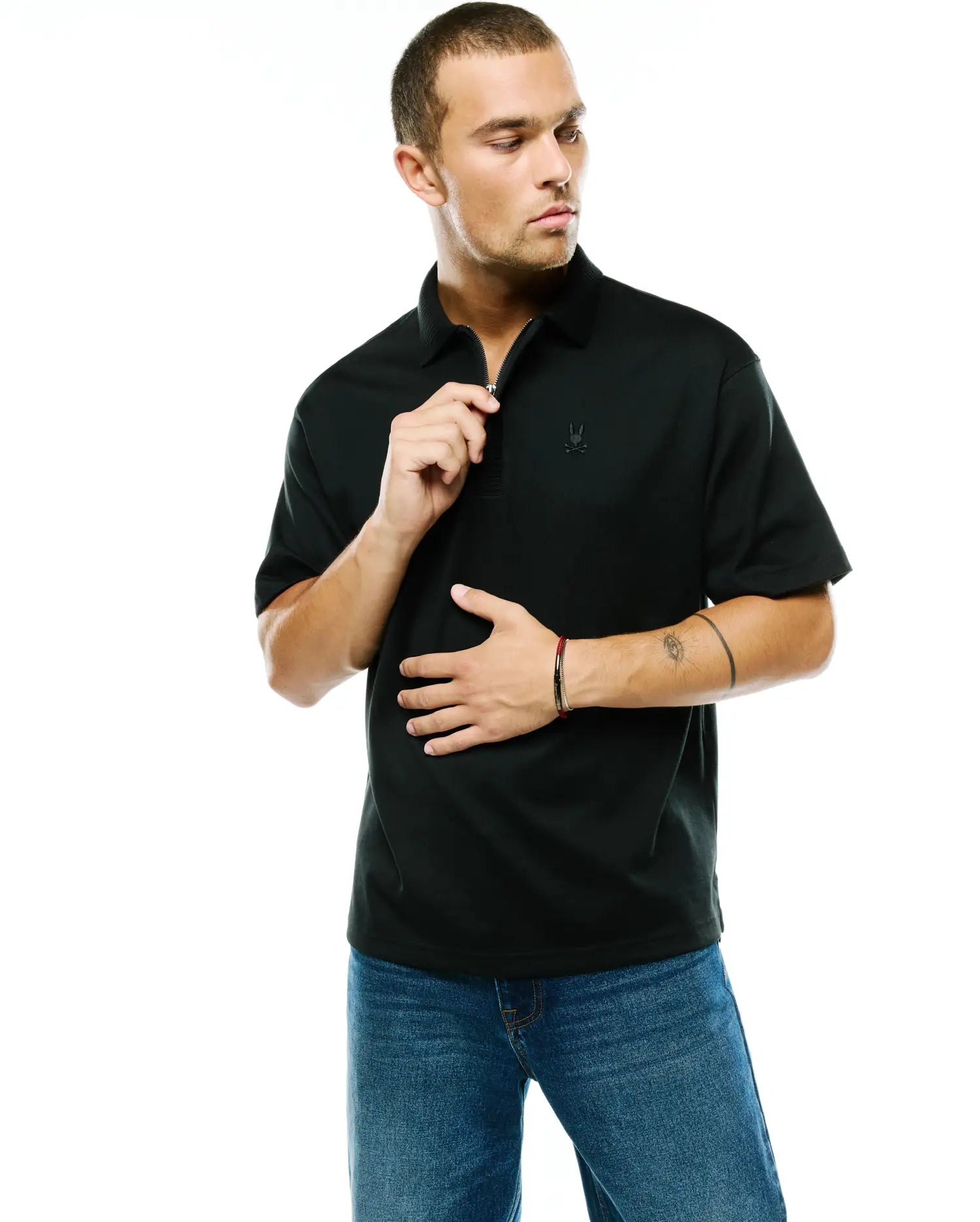 Men's Nolen Oversized Jersey Polo in black, featuring a smooth jersey fabric, a zippered placket, and a small, tonal embroidered Psycho Bunny skull logo on the left chest. (1)