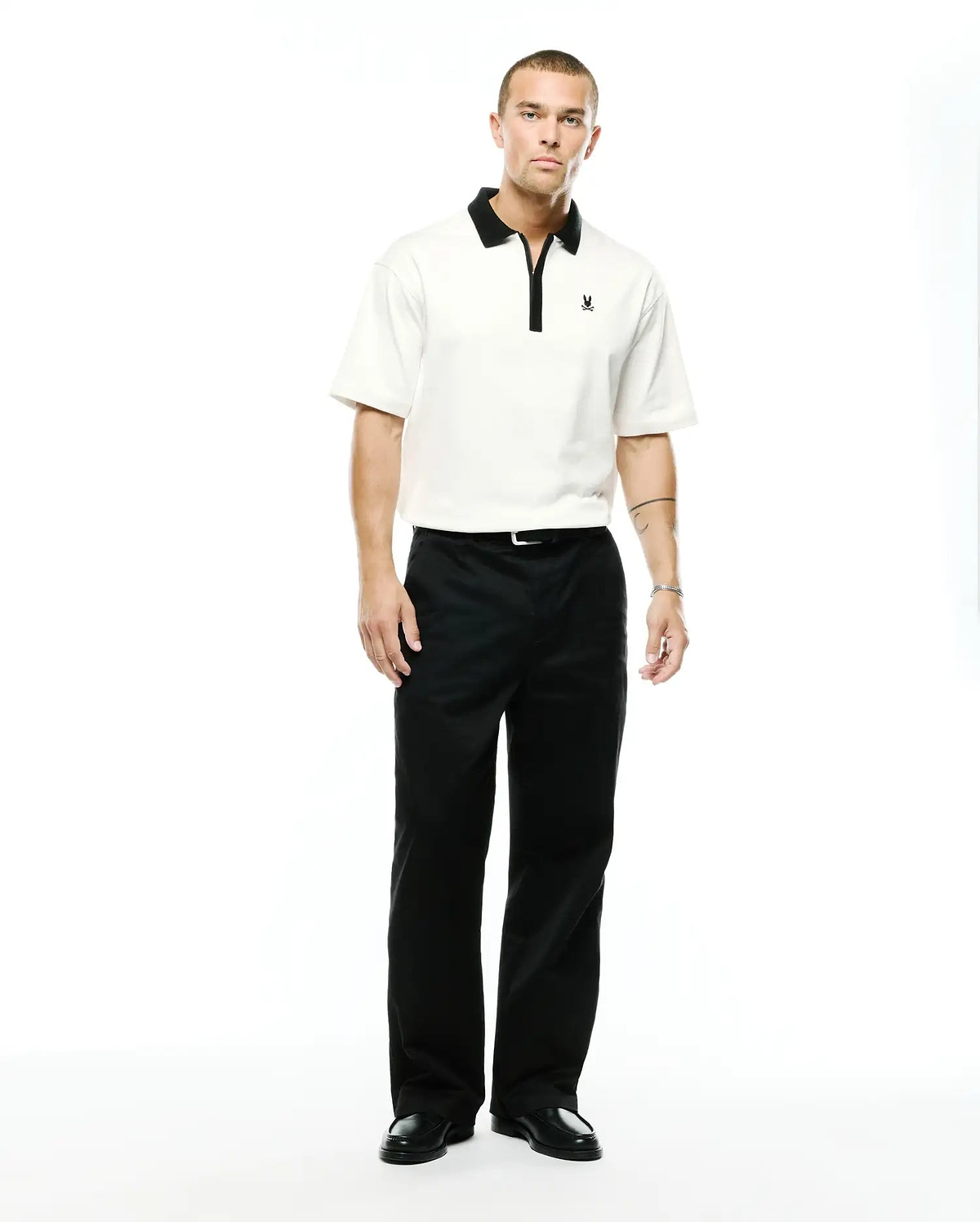 Men's Nolen Oversized Jersey Polo in cream, featuring a black contrast collar, black zipper placket, and a small embroidered black Psycho Bunny skull logo on the left chest. (4)