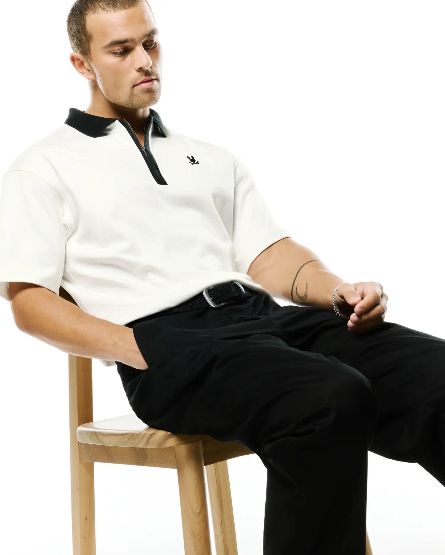 Men's Nolen Oversized Jersey Polo in cream, featuring a black classic collar, black zippered placket, and a small black embroidered Psycho Bunny skull logo on the left chest. (3)