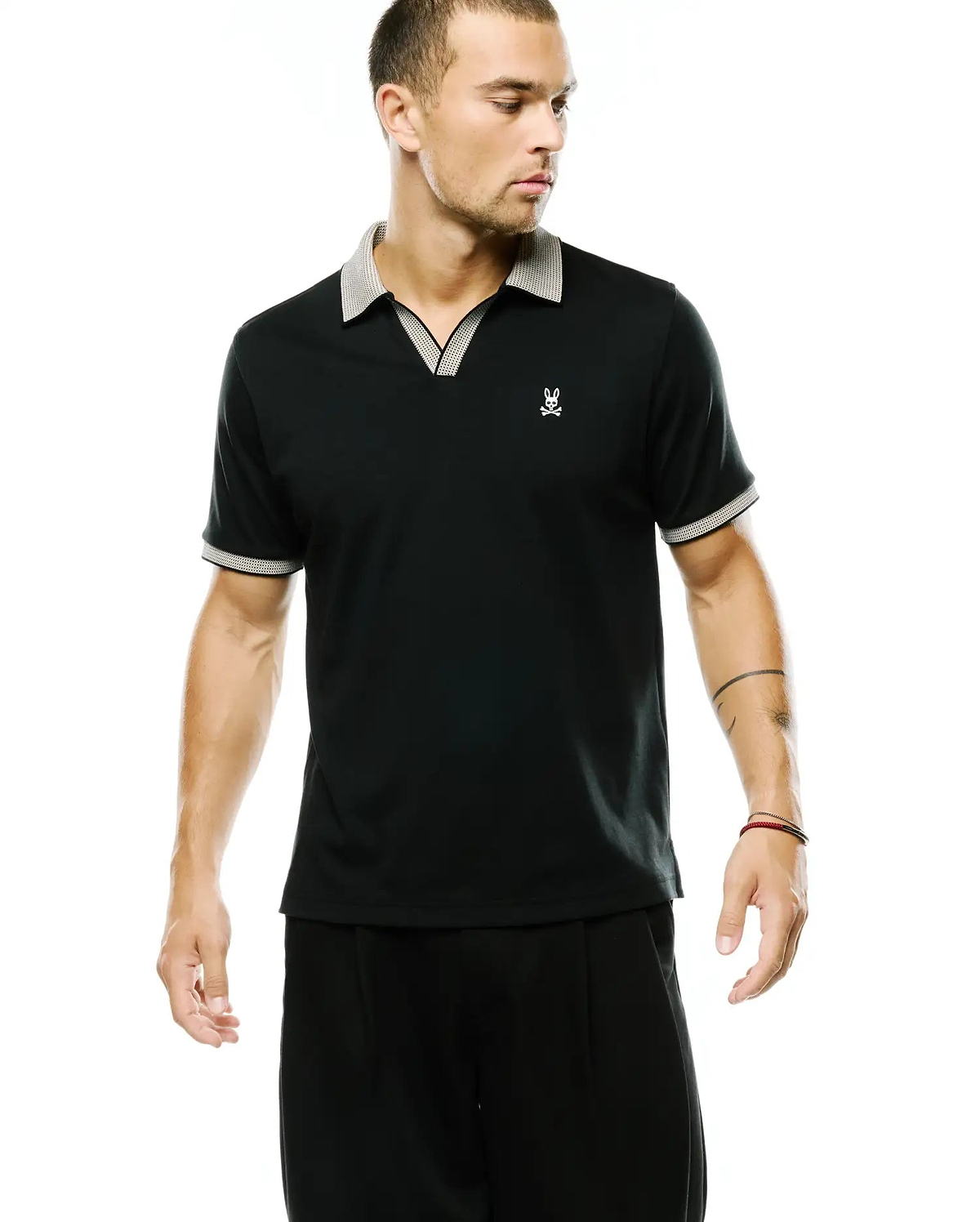 Men's Teddy Johnny Collar Polo, black jersey knit, classic fit, featuring a white textured V-neck collar and cuffs, with a small embroidered white Psycho Bunny skull logo on the left chest. (1)